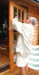 Chris cleaning the residue off the windows in the new doors using a razor blade (in a holder) -s.JPG